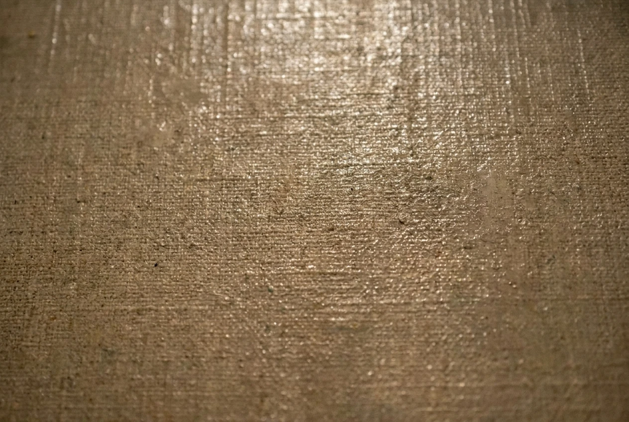 A close-up of a thinly painted passage where the woven linen canvas texture shows through the pigment, with an uneven varnish sheen creating patchy reflections of warm gallery light across the surface.